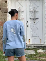 Cárdigan celeste con apliques plateados en forma de llamas y parches en los codos.