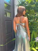 Vestido largo con escote en V, estampado en tonos rojizos y rosados, con un patrón ondulado. Presenta cut-outs laterales bajo el busto y breteles finos que se cruzan en la espalda.