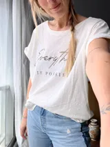 Remera blanca de algodón con cuello redondo y mangas cortas con dobladillo. Estampado frontal con la frase "Everything is possible" en letras negras con detalles dorados.