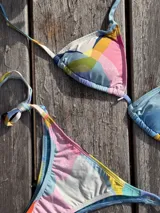 Conjunto de bikini azul con corpiño de triángulos movibles con almohadillas desmontables, que se ata al cuello y a la espalda. La bombacha es vedetina con tiritas a los costados para atar a medida de la cadera.