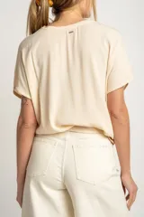 Blusa color crema de poliéster con mangas cortas y corte holgado.