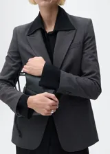 Chaqueta gris con estampado de micro pata de gallo, cuello con solapa, cierre frontal con botón, dos bolsillos delanteros con ribete y solapa, manga larga abotonada y forro interior.