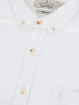 Camisa blanca de gasa lisa, de corte clásico, con cuello abotonado y bolsillo en el pecho. Marca La Dolfina.