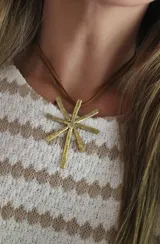 Collar con dije de estrella de bronce con textura martillada, colgando de un cordón doble de cuero sintético marrón.