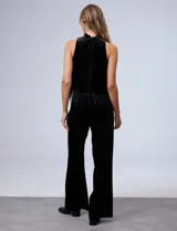 Conjunto de musculosa y pantalón en terciopelo negro, marca Julia Jordan. Blusa de cuello alto y terminación de ruedo con plumas. Pantalón con cintura elastizada.