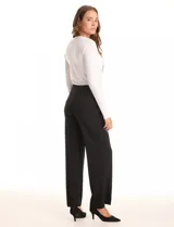 Pantalón negro de crepe con corte recto y silueta fluida, marca Zac & Rachel. Tiro medio-alto con pretina ancha y plana. Presenta una cartera cruzada desplazada hacia el lateral y aplique de botones metálicos. Laterales con bolsillos y tachas metálicas.