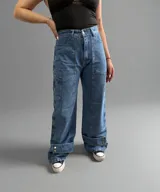 Pantalón de jean azul con efecto lavado, corte wide leg, bolsillos laterales y detalle de botones en el ruedo.