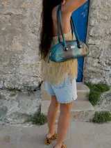 Cartera tipo baguette color marrón con asa corta con detalle de bolitas de madera.