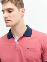 Remera polo blanca de piqué con cuello y puños en azul marino. Tiene tapeta de dos botones y bolsillo de parche en el pecho.