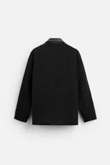 Parka negra de algodón con cuello solapa de cuero sintético, corte recto, acolchada y con cierre frontal de botones.