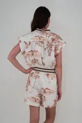 Short de lino color crudo con estampado de paisaje en tonos marrones. Tiene bolsillos laterales, cintura elástica con cordón ajustable y ruedo festoneado.