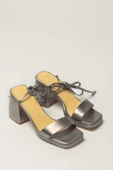 Sandalias plateadas de cuero con tacón bloque, plataforma delantera y tiras finas para atar al tobillo.