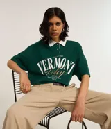 Camisa polo verde oscuro de algodón con cuello blanco contrastante, cierre de botones y mangas cortas. Estampa frontal con lettering "Vermont Valley".