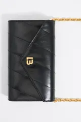 Mini bolso negro con diseño acolchado y logo dorado en el frente. Incluye correa de cadena dorada.