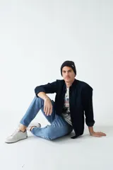 Camisa de pana color verde militar, de corte regular, con cuello clásico y cierre frontal con botones.