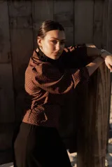 Camisa marrón con lunares blancos, corte clásico, cuello camisero, mangas 3/4 abullonadas y lazo ajustable en la cintura.