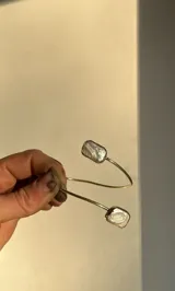Pulsera rígida abierta de bronce dorado con dos perlas barrocas rectangulares en los extremos.