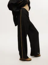 Pantalón de lino color marrón claro, de pierna ancha y tiro alto. Presenta un pequeño elástico en la parte trasera de la pretina y detalle al costado tipo naval.