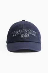 Gorra de béisbol azul marino con bordado frontal de la leyenda "New York" y el año "1996" en color blanco.