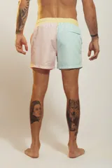 Short de baño para hombre, tiro medio, con estampado tropical en tonos rosados, verdes y blancos. Posee cintura elástica con cordón de ajuste trenzado y bolsillos laterales.