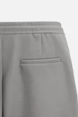 Bermuda color beige de corte recto, con cintura elástica ajustable con cordón, detalle de pliegues frontales, bolsillos laterales y bolsillos de vivo en la espalda.