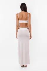Conjunto de top y short color beige confeccionado en tela brillante. El top cuenta con arco metálico en el busto, tiras para atar en el hombro y ganchos lenceros en la espalda. El short es de tiro alto con cintura elastizada y bolsillos laterales.
