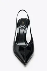 Zapato destalonado acharolado color negro, con tacón fino y punta. Tiene una tira trasera con elástico.