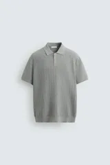 Polo gris de punto con textura, corte regular fit, cuello solapa y cierre frontal con botones.