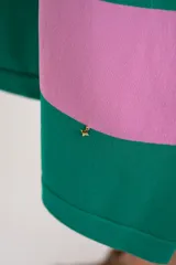 Vestido midi de tejido suave y ligero, con cuello redondo y mangas cortas. Presenta un patrón de rayas horizontales anchas en color verde oscuro y rosado. El vestido tiene aberturas laterales en el ruedo.