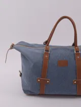 Bolso de viaje negro con detalles en cuero marrón, doble asa de mano y cierre superior con cremallera.