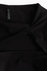 Top corto negro de punto elástico con escote asimétrico, detalle girado en el frente, abertura en el pecho, mangas largas y bajo recto.
