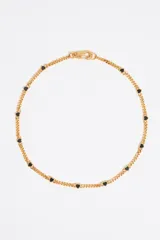 Collar dorado con cadena de eslabones y pequeños dijes de corazones negros.