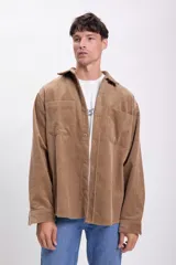 Sobrecamisa de pana color tostado, de corte recto, con cuello camisero, cierre frontal con botones, dos bolsillos de parche en el pecho y mangas largas con puños abotonados.
