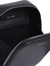 Cartera tipo bandolera Calvin Klein color negro, de forma rectangular con bordes redondeados y cierre de cremallera. Tiene correa ajustable con logo y el logo de la marca en el frente.