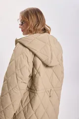 Campera color beige con capucha, cierre frontal con cremallera y diseño acolchado con costuras en forma de rombos.