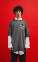 Remera oversize de algodón premium, color gris oscuro con efecto gastado (acid wash), con cuello redondo y manga corta. Presenta un pequeño estampado de Mickey Mouse en el pecho.