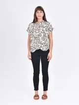 Camisa de manga corta con estampado animal print en tonos beige, marrón y negro. Tiene cuello mao y cierre frontal con botones.