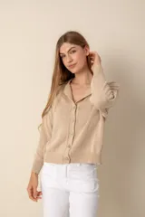 Cárdigan color beige de tejido de punto, con cuello camisero, cierre frontal con botones y mangas largas.