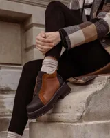 Botines de cuero negro con paneles laterales de charol, cierre frontal con cremallera y suela track.