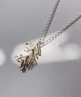 Collar plateado con dije en forma de coral. El dije tiene una textura rugosa y un diseño intrincado que imita la forma natural del coral. La cadena es de eslabones finos y delicados.