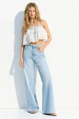 Jean celeste de denim rígido de algodón con cinco bolsillos, corte wide leg, cintura extra alta, cierre con botón y largo levemente largo. Inspirado en los 70.