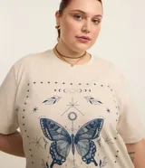 Remera color beige de corte alargado, cuello redondo y mangas cortas. Estampado frontal con una mariposa azul rodeada de elementos celestiales.