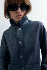 Sobrecamisa de denim metalizado color azul con cuello clásico, cierre frontal con botones, bolsillos de parche en el pecho y mangas largas.