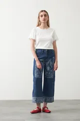 Remera de tejido acanalado color blanco, con cuello redondo y mangas cortas que presentan un detalle de terminación en puntilla en los bordes.