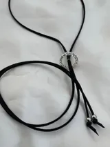 Gargantilla negra con dije circular plateado con strass y tiras largas.