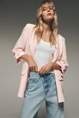 Blazer color marrón oscuro, de corte recto, con cuello solapa y hombreras. Tiene mangas 3/4 con trabilla y botón dorado, y bolsillos delanteros con solapa.