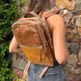 Mochila de cuero vacuno color marrón con diseño geométrico en la parte inferior. Tiene tres compartimentos, uno de ellos acolchado para laptop, y cierre con cremallera.