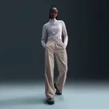 Pantalón deportivo Nike Windrunner Woven de mujer, color gris, corte holgado, cintura elastizada con cordón ajustable y bolsillos laterales.