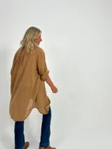 Sobrecamisa color camel de corte recto y largo midi, con cuello camisero, mangas largas con puños abotonados y bolsillos de parche en el pecho.
