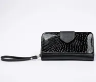 Billetera dorada con cierre metálico y solapa con el logo de la marca Vanitas. Tiene múltiples compartimentos para tarjetas y billetes. Incluye correa de muñeca extraíble.